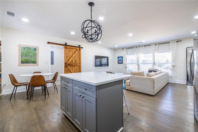 kitchen featuring recessed lighting, gray cabinets, a barn door, dark wood-type flooring, and a kitchen island