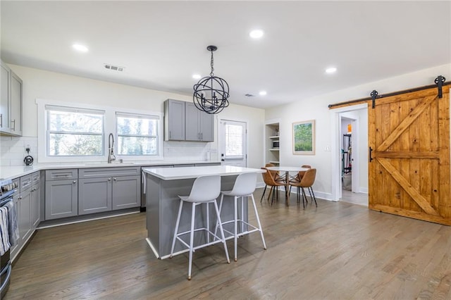 kitchen featuring visible vents, a sink, gray cabinetry, and a barn door