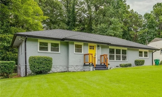 view of front of house featuring crawl space, roof with shingles, a front lawn, and brick siding