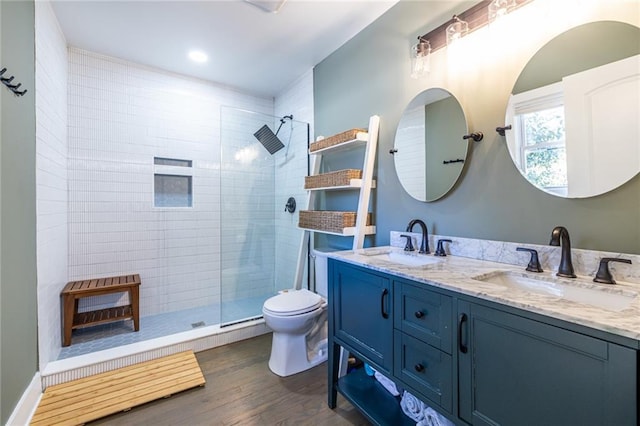 bathroom with a tile shower, wood finished floors, and a sink