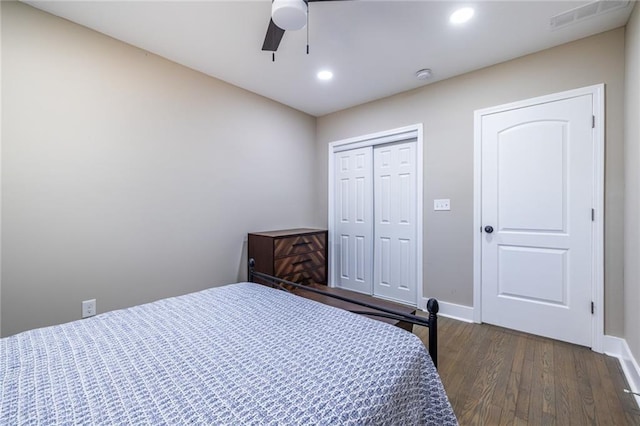 bedroom featuring dark wood-type flooring, visible vents, a ceiling fan, baseboards, and a closet