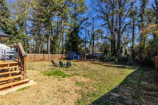 view of yard with a storage shed, an outdoor structure, a fenced backyard, and a wooden deck