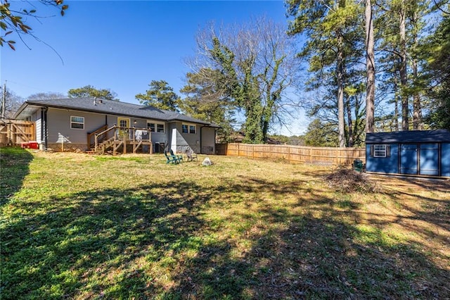 view of yard with a fenced backyard, a storage unit, a wooden deck, and an outbuilding