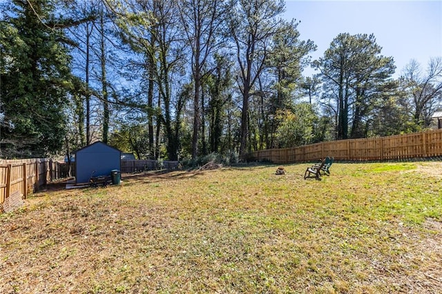 view of yard with a storage shed, a fenced backyard, and an outbuilding