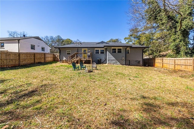 rear view of house with a lawn and a fenced backyard