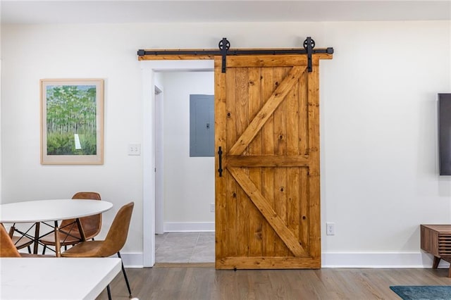 dining area with a barn door, electric panel, baseboards, and wood finished floors