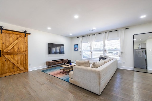 living area with a barn door, baseboards, wood finished floors, and recessed lighting