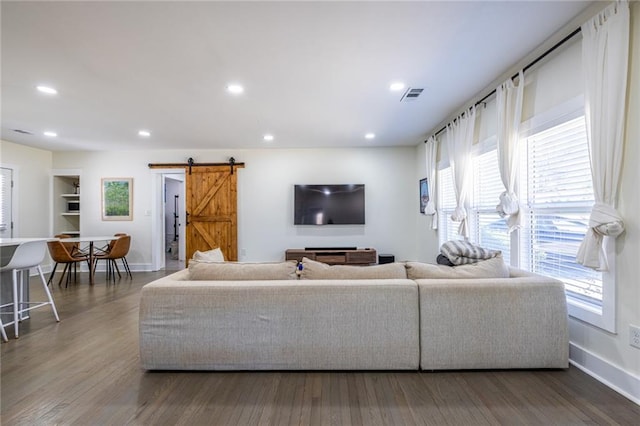 living room featuring a barn door, visible vents, wood finished floors, and recessed lighting