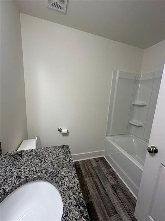 bathroom with hardwood / wood-style flooring, bathing tub / shower combination, and sink