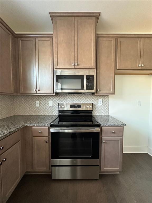 kitchen with dark hardwood / wood-style flooring, light stone countertops, stainless steel appliances, and tasteful backsplash