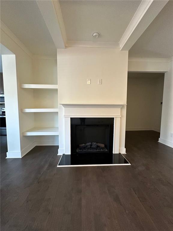 unfurnished living room featuring built in shelves, dark hardwood / wood-style flooring, and ornamental molding