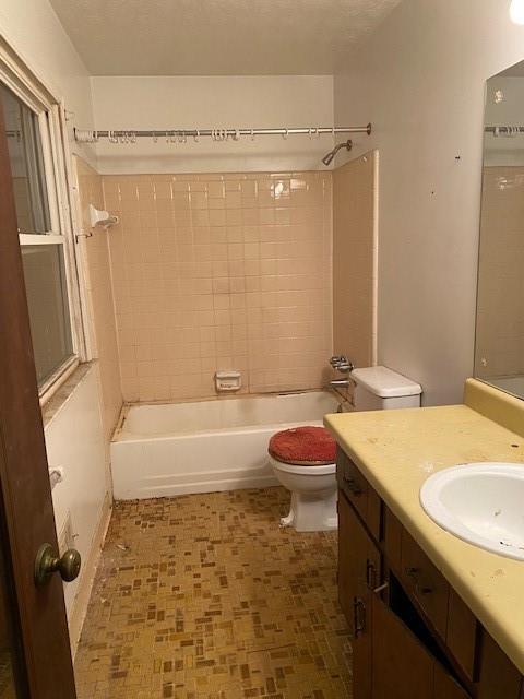 full bathroom featuring vanity, tiled shower / bath, a textured ceiling, and toilet