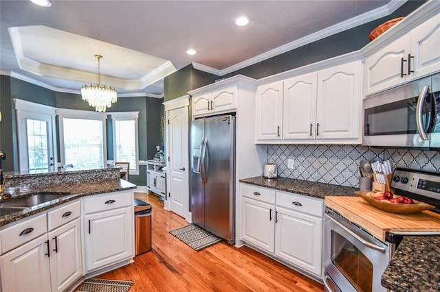 4742 Thunder River Dr, Gainesville, GA 30506 - kitchen with appliances with stainless steel finishes, light wood finished floors, white cabinetry, pendant lighting, and ornamental molding