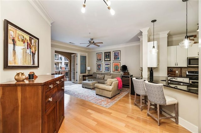 living room featuring light hardwood / wood-style floors, ceiling fan, crown molding, and sink