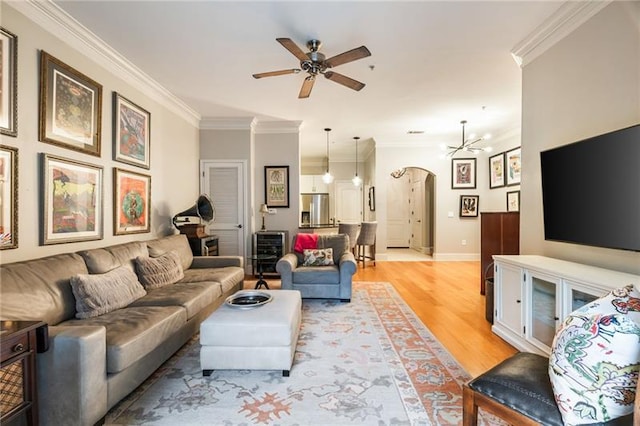 living room featuring ceiling fan with notable chandelier, ornamental molding, and light hardwood / wood-style flooring