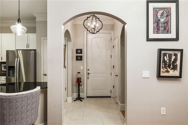 tiled entrance foyer with an inviting chandelier and crown molding