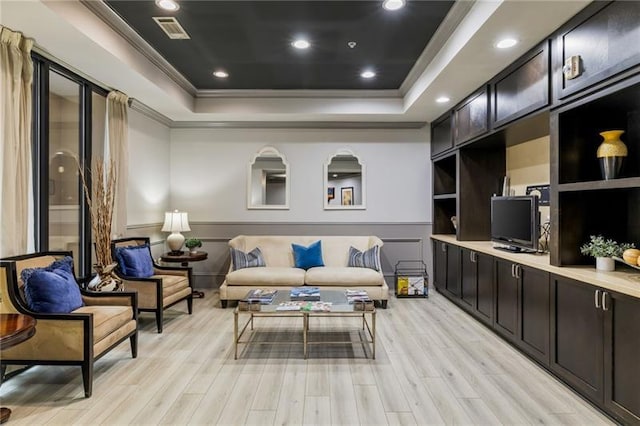 sitting room featuring crown molding, light hardwood / wood-style flooring, and a tray ceiling