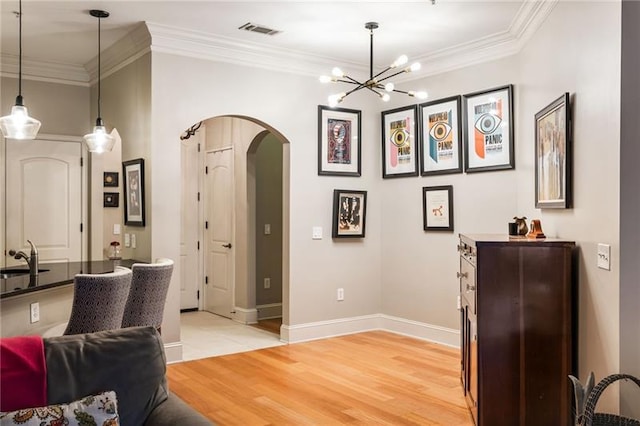 interior space with sink, light hardwood / wood-style flooring, ornamental molding, and a notable chandelier