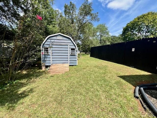 view of yard with a storage shed, an outbuilding, and fence