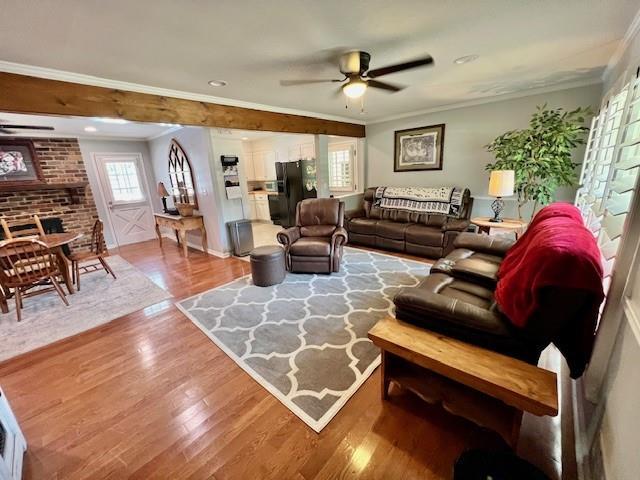 living room with a ceiling fan, crown molding, and wood finished floors