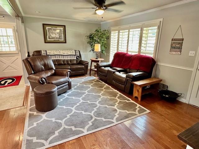 living room with ceiling fan, wood finished floors, and ornamental molding