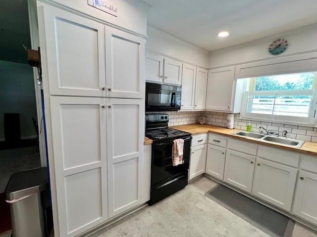 kitchen with a sink, black appliances, white cabinetry, backsplash, and butcher block counters