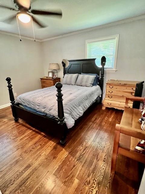 bedroom featuring dark wood finished floors, crown molding, a ceiling fan, and baseboards