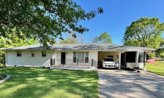 ranch-style house featuring a carport, a front lawn, and driveway