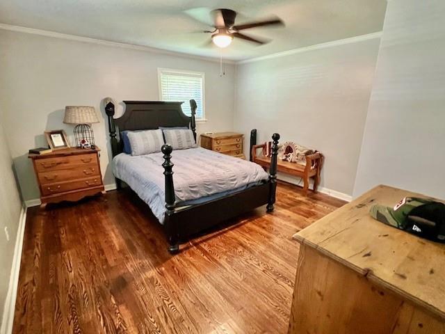 bedroom with ceiling fan, wood finished floors, baseboards, and ornamental molding