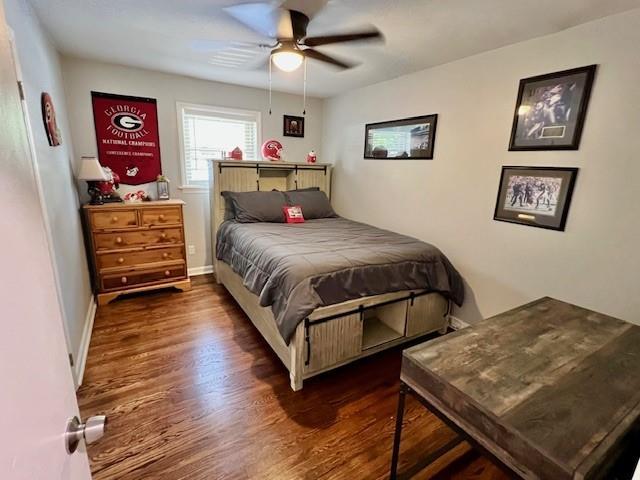 bedroom with a ceiling fan, wood finished floors, and baseboards