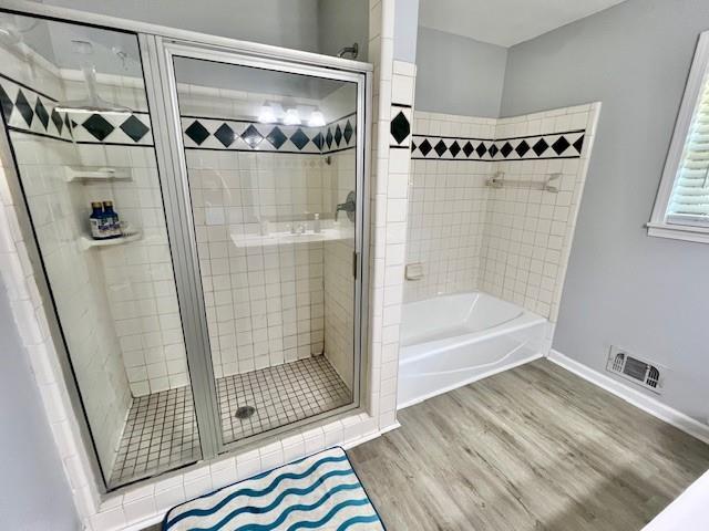 bathroom with a stall shower, visible vents, a garden tub, and wood finished floors