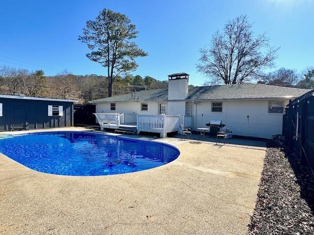 outdoor pool with a patio and a wooden deck