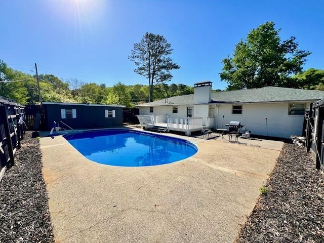 view of pool featuring a patio area, a fenced backyard, a wooden deck, and a fenced in pool