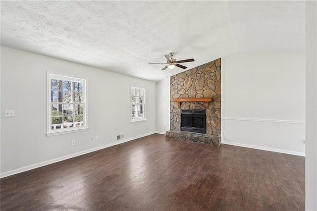 unfurnished living room with lofted ceiling, a textured ceiling, a stone fireplace, wood finished floors, and visible vents