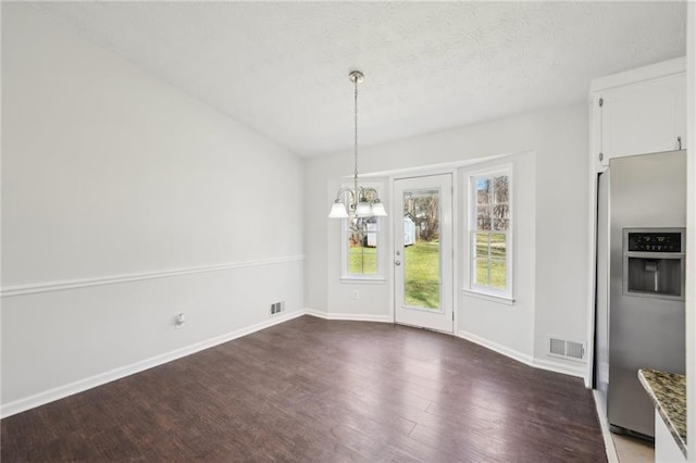 unfurnished dining area featuring baseboards, a notable chandelier, visible vents, and dark wood-type flooring