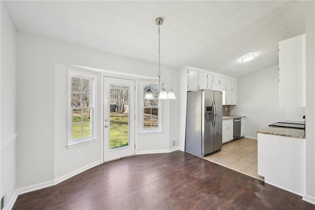 kitchen with a textured ceiling, stainless steel appliances, white cabinets, light wood-type flooring, and an inviting chandelier