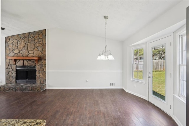 unfurnished living room with lofted ceiling, a stone fireplace, dark wood-type flooring, and visible vents