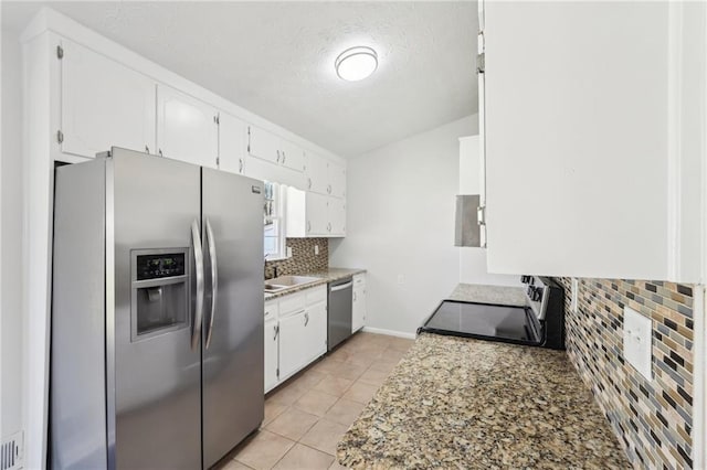 kitchen featuring light tile patterned floors, a sink, white cabinetry, appliances with stainless steel finishes, and tasteful backsplash