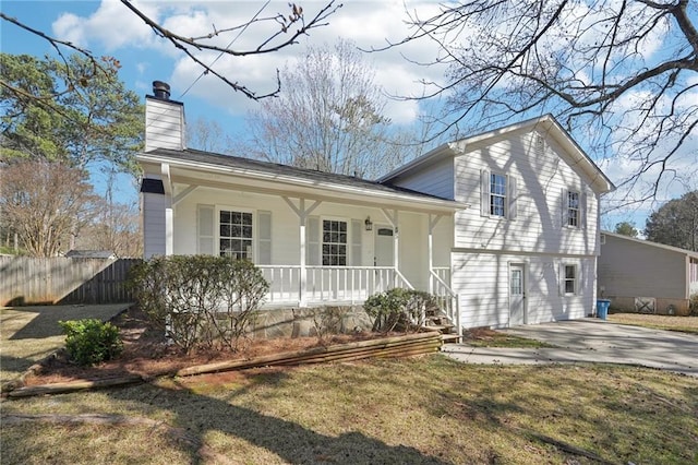 split level home featuring covered porch, fence, and a chimney