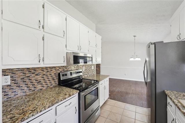 kitchen featuring light tile patterned floors, appliances with stainless steel finishes, backsplash, and white cabinets