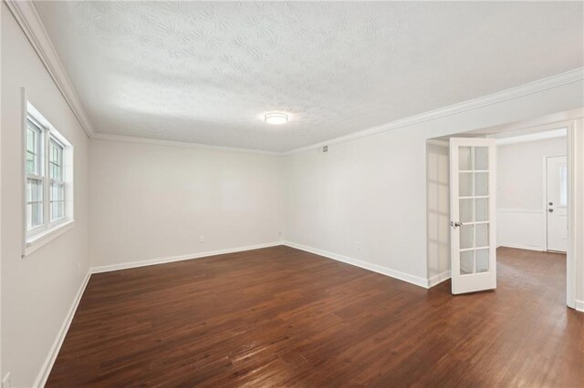 unfurnished room featuring dark wood-style flooring, crown molding, a textured ceiling, and baseboards