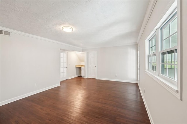 empty room featuring a textured ceiling, dark wood-type flooring, visible vents, baseboards, and crown molding