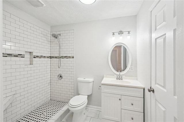 full bathroom with baseboards, toilet, a tile shower, a textured ceiling, and vanity