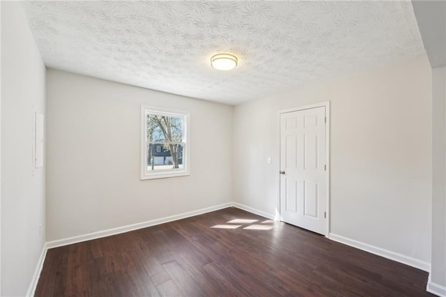 unfurnished room featuring a textured ceiling, baseboards, and wood finished floors