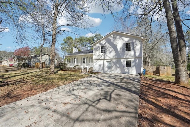 tri-level home with covered porch, driveway, and a chimney