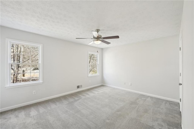 empty room with visible vents, a ceiling fan, carpet flooring, a textured ceiling, and baseboards