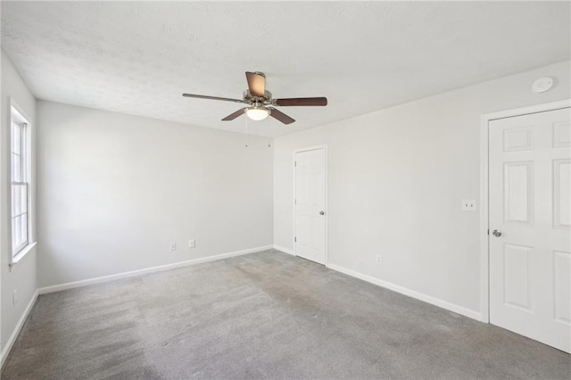 empty room with a textured ceiling, carpet floors, ceiling fan, and baseboards