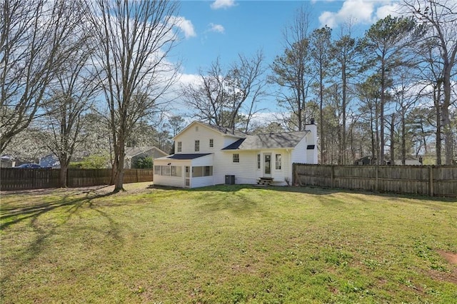 rear view of property featuring a chimney, a fenced backyard, a yard, and central AC