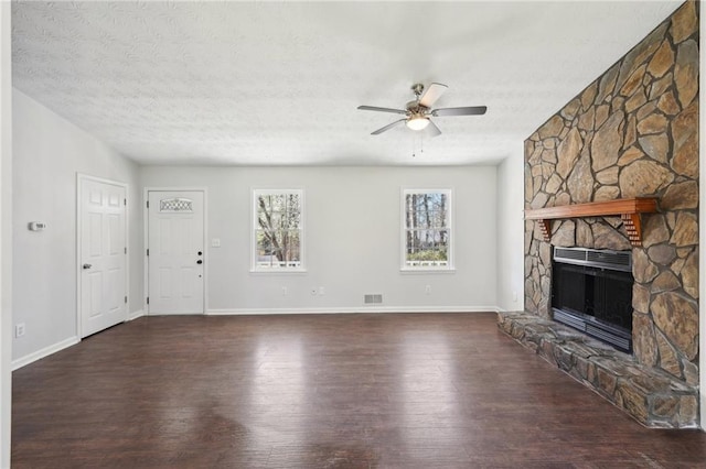 unfurnished living room featuring a textured ceiling, a ceiling fan, wood finished floors, and a stone fireplace