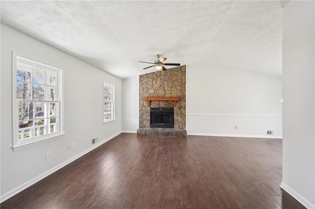 unfurnished living room featuring visible vents, lofted ceiling, wood finished floors, a textured ceiling, and a stone fireplace